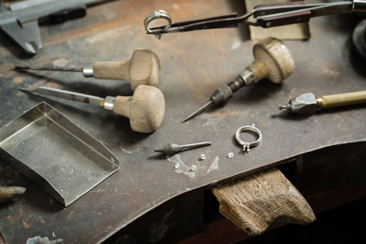 An abandoned jeweler&rsquo;s workstation with tools, ring settings, and diamonds