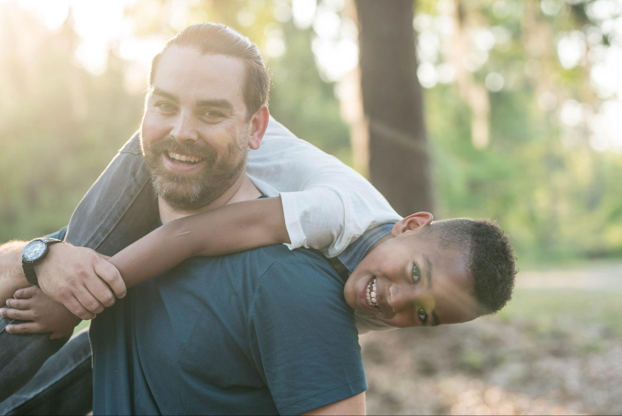 A father and son play in a park during a sunset.