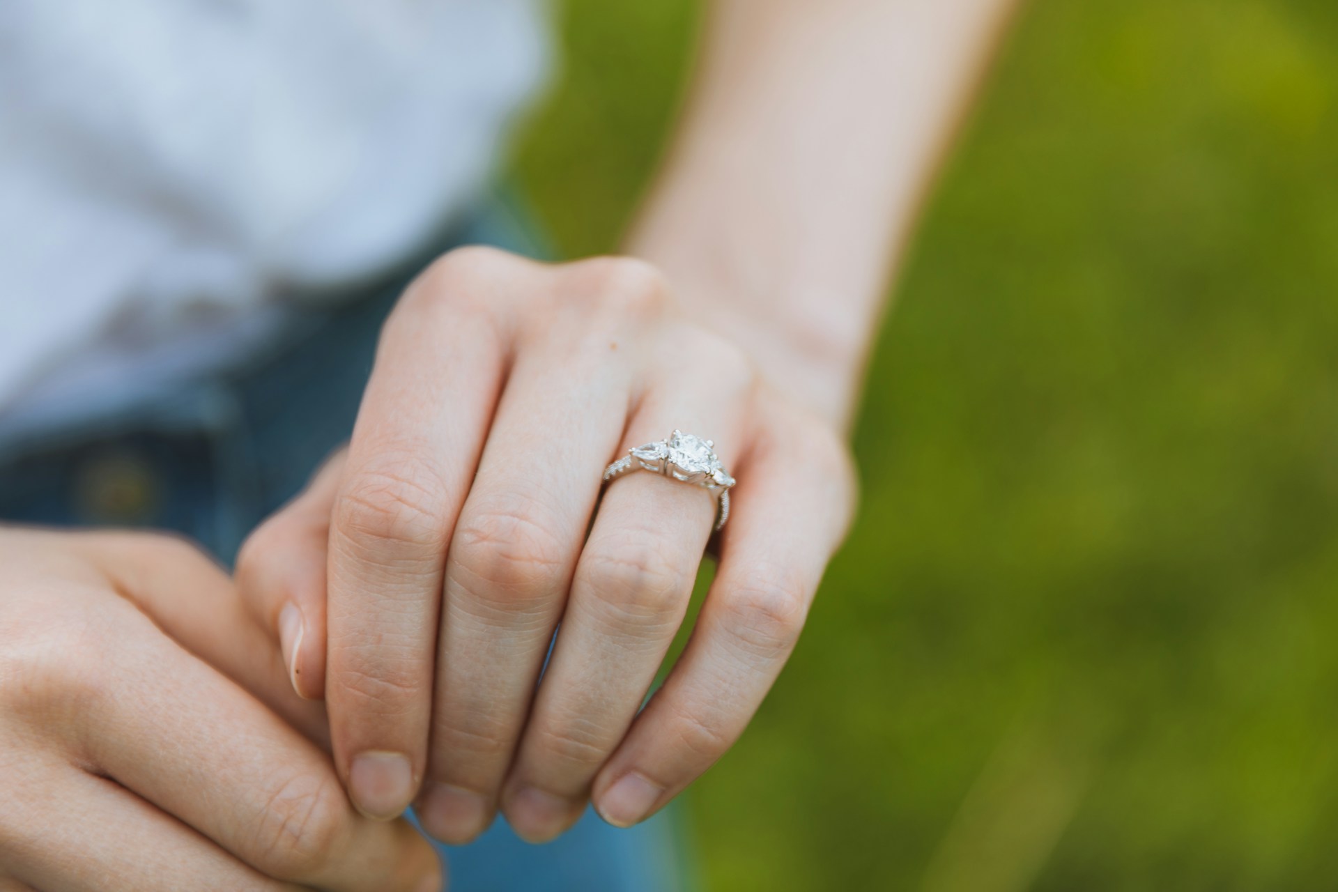 a woman&rsquo;s hand extended and adorned with a three stone engagement ring